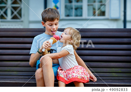 Big brother giving his ice cream to little sister outdoor Big brother giving his ice cream to little sister outdoor 49092833