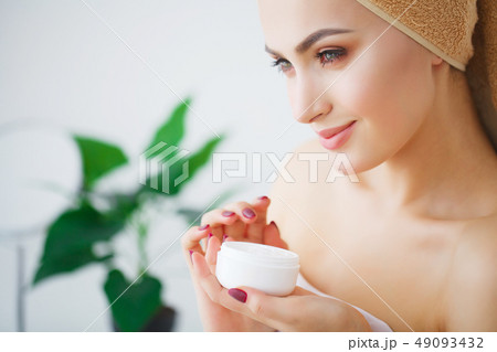Portrait of beautiful woman applying cream on face Portrait of beautiful woman applying cream on face 49093432
