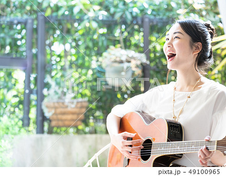 ギター 女性 弾き語りの写真素材