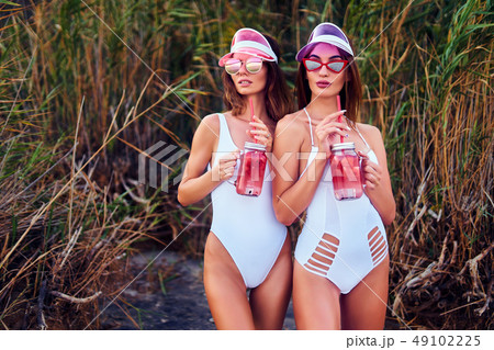 Trendy girls in swimsuits holding lemonades Trendy girls in swimsuits holding lemonades 49102225