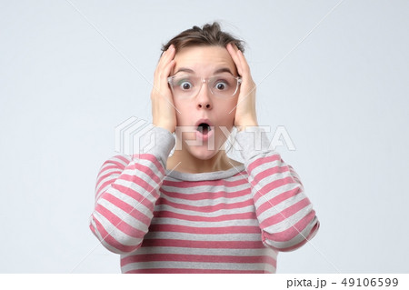Young surprised woman clasping head in hands. 49106599