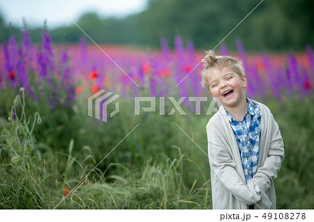 Little cute boy in field with red poppies and blue sky Little cute boy in field with red poppies and blue sky 49108278