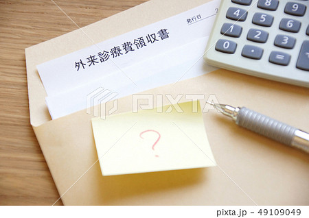 封筒に入った病院の医療費の領収書と電卓とペンとはてなマークが書かれた付箋紙 49109049