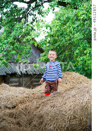The boy climbed up on a huge stack of straw The boy climbed up on a huge stack of straw 49112857