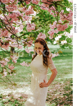 beautiful cute brunette girl bride in cream lace dress, with decoration on the hair, near the tree beautiful cute brunette girl bride in cream lace dress, with decoration on the hair, near the tree 49114273