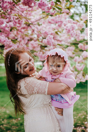 Loving mother and baby girl on background blooming pink flowers of cherry tree at springtime Loving mother and baby girl on background blooming pink flowers of cherry tree at springtime 49114275