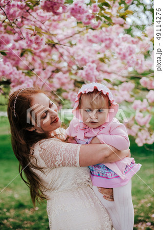 Loving mother and baby girl on background blooming pink flowers of cherry tree at springtime Loving mother and baby girl on background blooming pink flowers of cherry tree at springtime 49114276