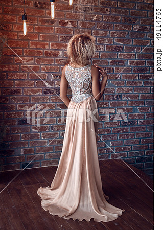 Portrait of attractive afro american young woman in tight gold dress in a luxury apartment. Beauty 49114765