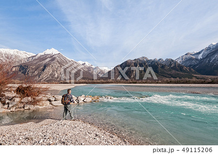 Man hiker on shore of river looking the mountains. 49115206