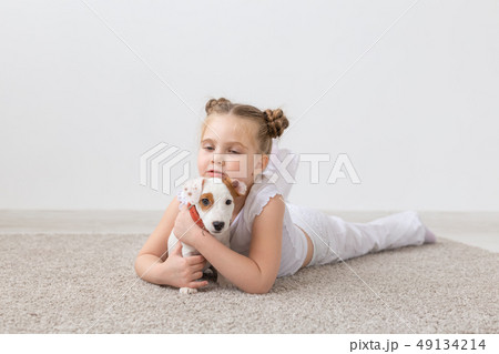 Pet, childhood and animal concept - Little child girl playing on the floor with puppy Jack Russell 49134214