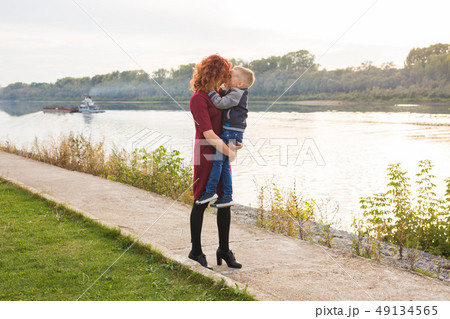 Motherhood and children concept - young mother with son in her arms near the river 49134565