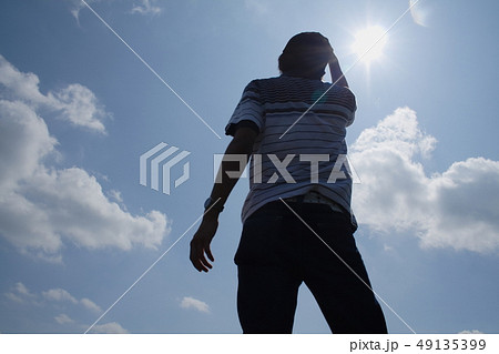 空を見上げる若者の後ろ姿の写真素材