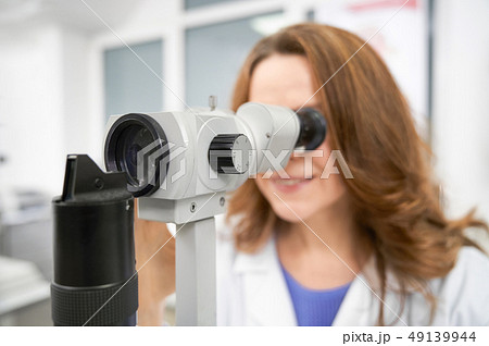 Close up of ophthalmologist looking in slit lamp. Close up of ophthalmologist looking in slit lamp. 49139944