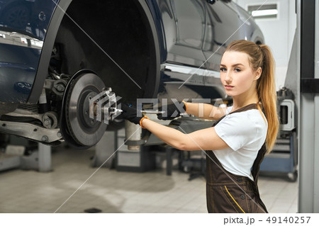 Pretty girl working as mechanic in autoservice, fixing car. 49140257