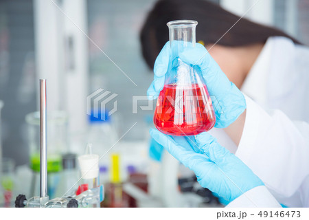 Hand holding flask with red color liquid  49146473