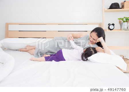 Pregnant mother breast feeding daughter on bed  49147760
