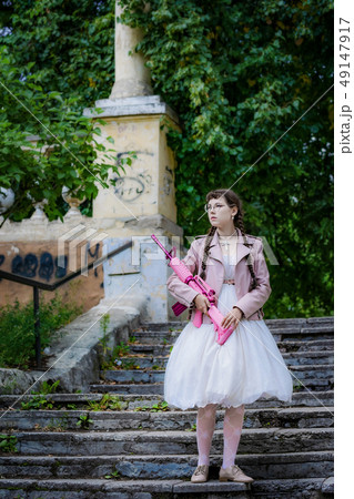 girl with a pink rifle go up on steps of stairs. 49147917