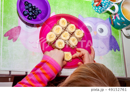 Little girl eating banana bread for breakfast Little girl eating banana bread for breakfast 49152761