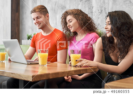 Group of young people sitting at table, looking at laptop. Group of young people sitting at table, looking at laptop. 49160355