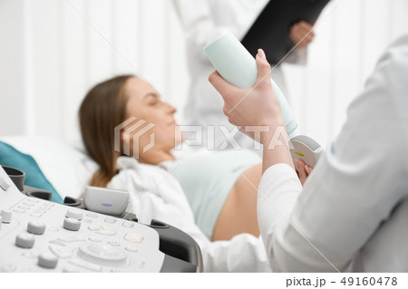 Ultrasound machine close up, pregnant woman on examination. Ultrasound machine close up, pregnant woman on examination. 49160478