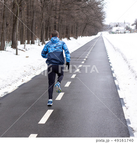 Man runner running on track in winter time Man runner running on track in winter time 49161740