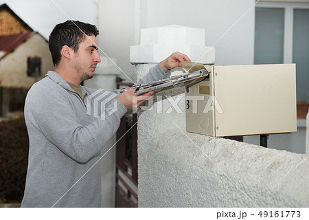 Man putting newspaper from the mailbox 49161773