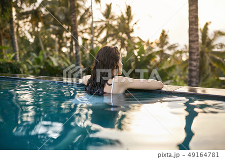 Woman in white swimsuit in outdoor pool on green jungle background 49164781
