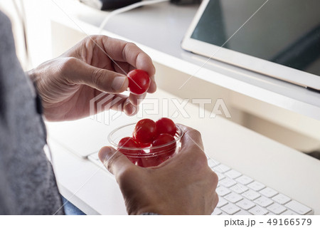 young man eating cherry tomatoes at the office young man eating cherry tomatoes at the office 49166579