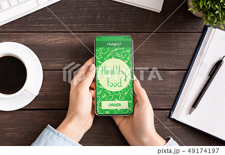 Female hand holding phone with app delivery food on screen Female hand holding phone with app delivery food on screen 49174197