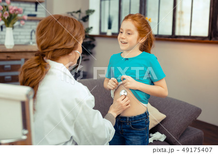Positive cute girl showing her belly to the doctor Positive cute girl showing her belly to the doctor 49175407