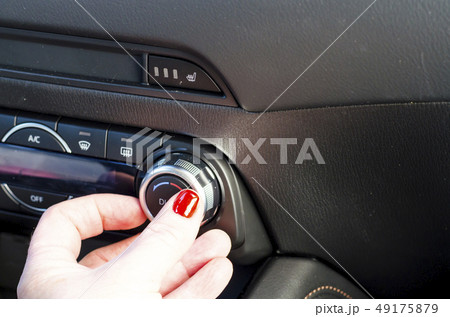 Female hand regulates climate control in car. Female hand regulates climate control in car. 49175879
