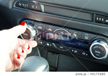 Female hand regulates climate control in car. Female hand regulates climate control in car. 49175880