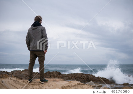 Traveler on the rocks near the sea looking far away at horizon. Rocky Atlantic Ocean Coastline and 49176090
