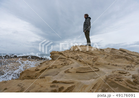 Traveler on the rocks near the sea looking far away at horizon. Rocky Atlantic Ocean Coastline and 49176091