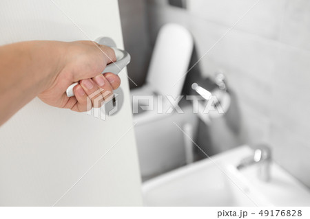 Male hand on handle of ajar door at toilet 49176828