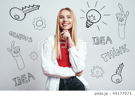 Full of ideas. Charming blonde woman in white shirt with hand on her chin looking at camera and 49177073