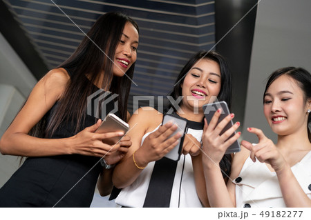 Three women friends chat with mobile phone device. 49182277