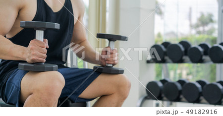 Muscular man bodybuilder training with dumbbells. Muscular man bodybuilder training with dumbbells. 49182916