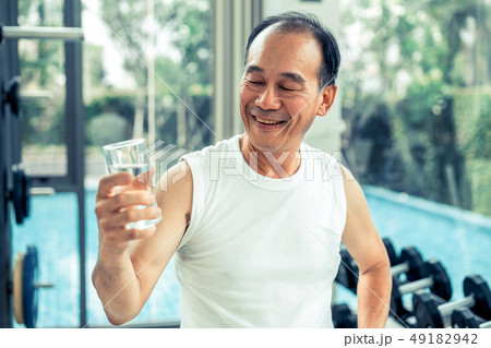 Senior man drink mineral water in fitness center. Senior man drink mineral water in fitness center. 49182942