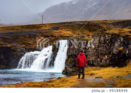 Traveler at Kirkjufellsfoss waterfall in Iceland Traveler at Kirkjufellsfoss waterfall in Iceland 49188946