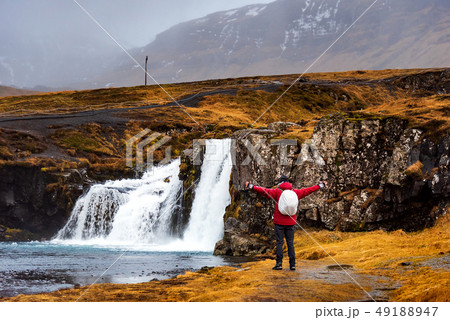 Traveler at Kirkjufellsfoss waterfall in Iceland Traveler at Kirkjufellsfoss waterfall in Iceland 49188947
