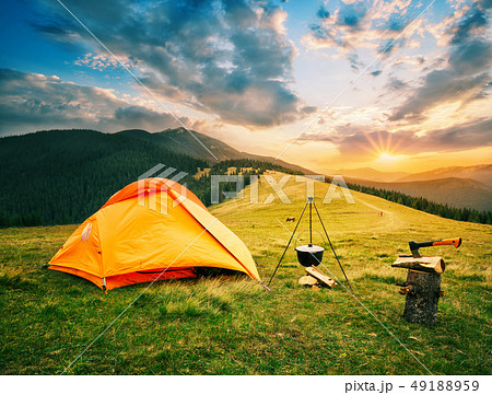 Tourist camp in mountains with tent and cauldron over fire at sunset 49188959