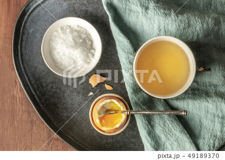 A soft-boiled egg with coarse sea salt and tea, shot from above on a dark rustic wooden background A soft-boiled egg with coarse sea salt and tea, shot from above on a dark rustic wooden background 49189370