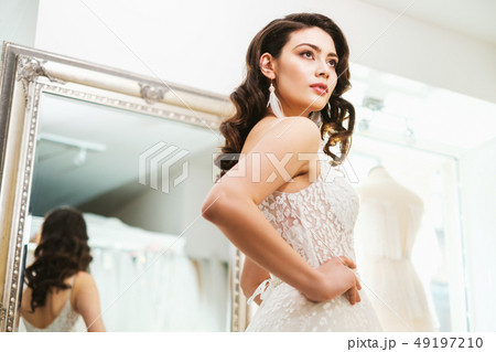 Beautifu bride choosing wedding dress in a wedding salon Beautifu bride choosing wedding dress in a wedding salon 49197210