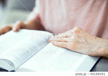 Middle Aged Woman Sitting On Sofa And Reading Bible 49199491