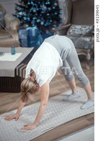 Cheerful mature woman making yoga exercises Cheerful mature woman making yoga exercises 49199645