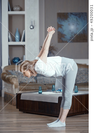 A 50 Year Old Woman Practices Yoga at Home in the Living Room. A 50 Year Old Woman Practices Yoga at Home in the Living Room. 49200031
