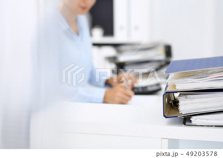 Binders with papers are waiting to be processed by business woman or bookkeeper back in blur Binders with papers are waiting to be processed by business woman or bookkeeper back in blur 49203578