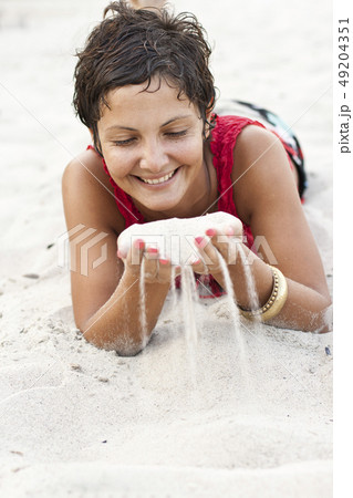 Attractive brunet woman in red lying on a sand. 49204351