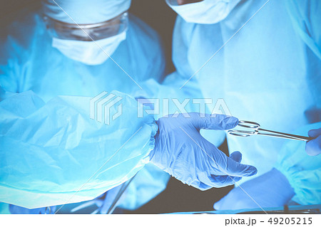 Surgeons hands holding surgical scissors and passing surgical equipment, close-up. Health care and 49205215